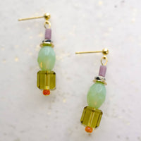 Pair of earrings with green and purple beads on a light background