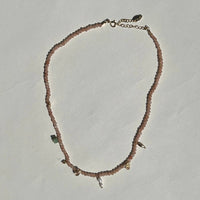 Necklace with small beads and chain on a light gray background