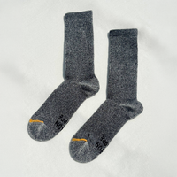 A pair of dark gray heather crew socks with black text and a small yellow accent on the toes, laid flat on a white textured background.