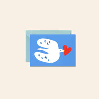 A mini greeting card with a blue background featuring a white dove holding a red heart