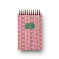 Pink notebook with floral pattern and pen holder on a white background