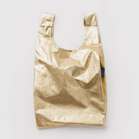 A metallic gold reusable plastic bag with integrated shoulder straps, shown against a plain light gray background. A small blue tag is visible on the right side.