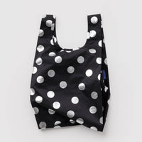 A reusable tote bag with a black base and large silver polka dots, photographed flat against a light gray background.
