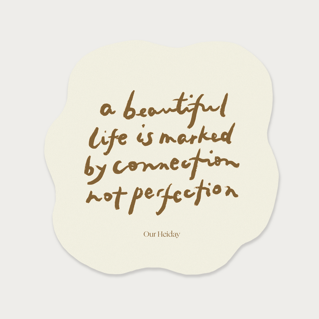 A cream-colored die-cut sticker with an organic wavy shape, featuring the quote 'a beautiful life is marked by connection not perfection' by our heiday 