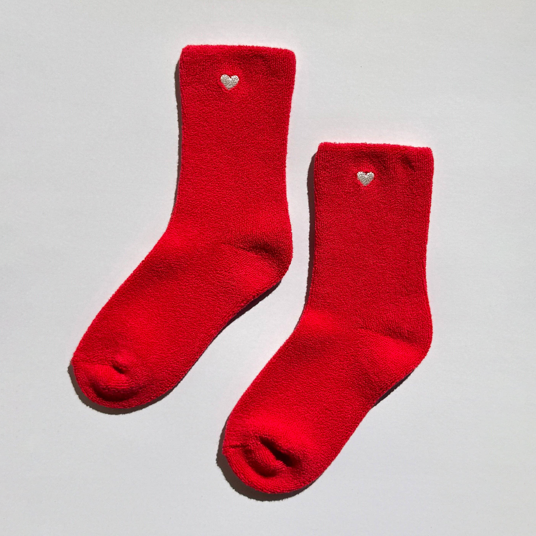 Pair of red fuzzy socks with embroidered hearts