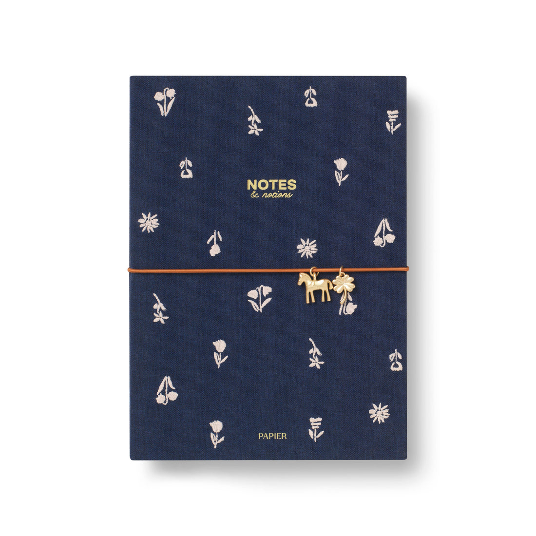 A navy blue hardcover A5 notebook with a gold elastic closure strap and a small gold horse charm. The cover features a delicate pattern of white flowers