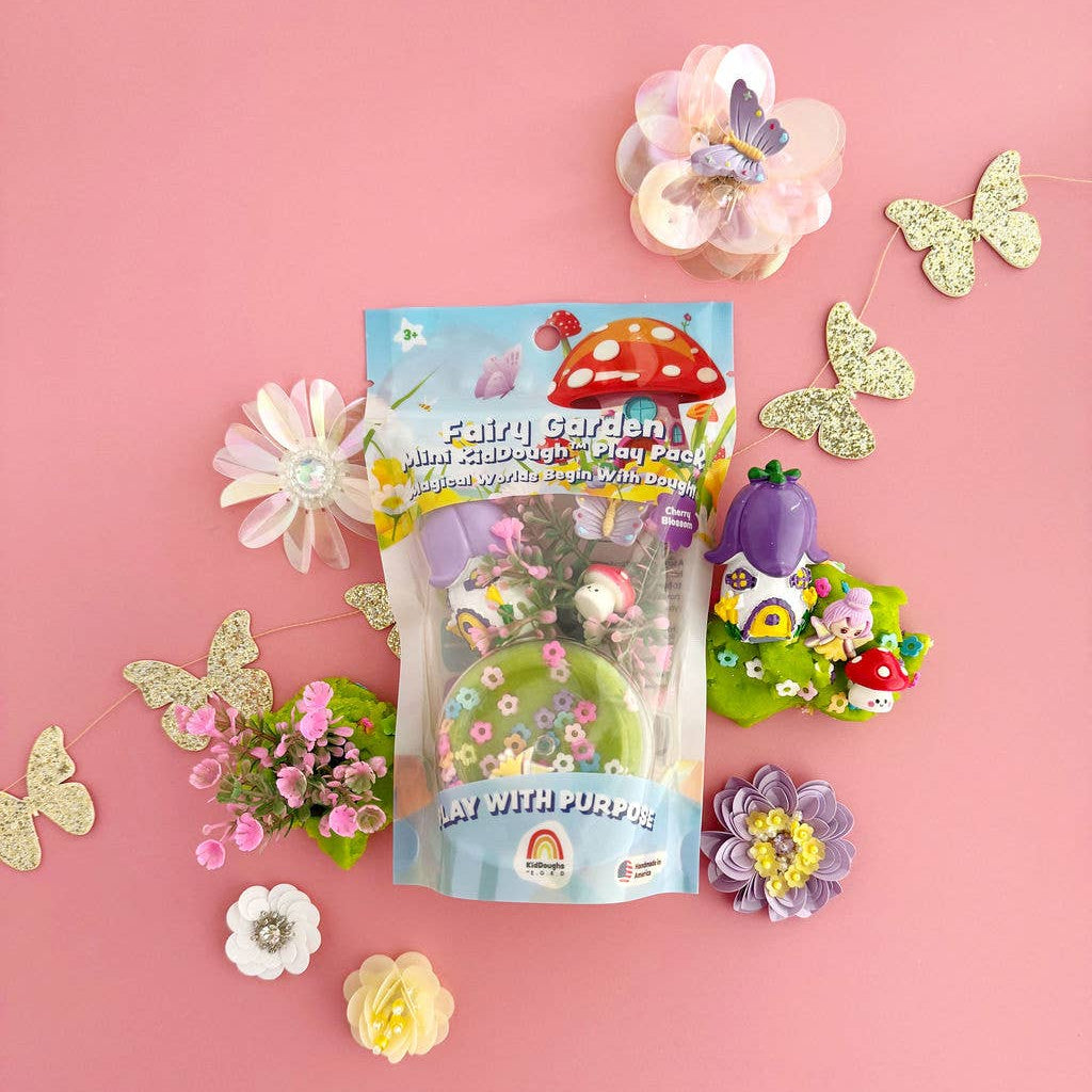 Fairy garden kit with small plants and decorative elements on a pink background