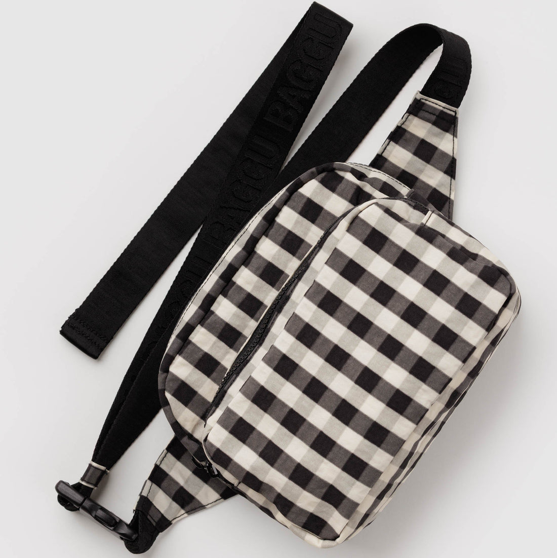 A black and white gingham check sling bag with a black adjustable shoulder strap, displayed on a clean light gray background.