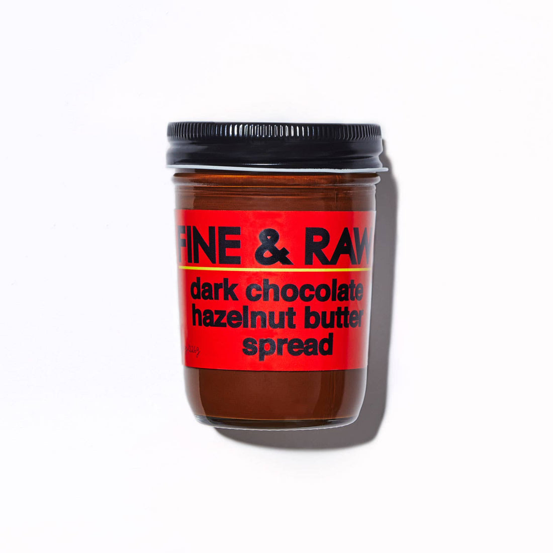 A jar of Fine & Raw dark chocolate hazelnut butter spread with a red label and black lid, photographed on a white background with a soft shadow.