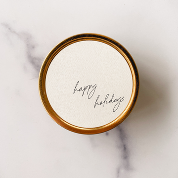 travel tin candle with "happy holidays" written on the lid olive leaf and lemon scented 