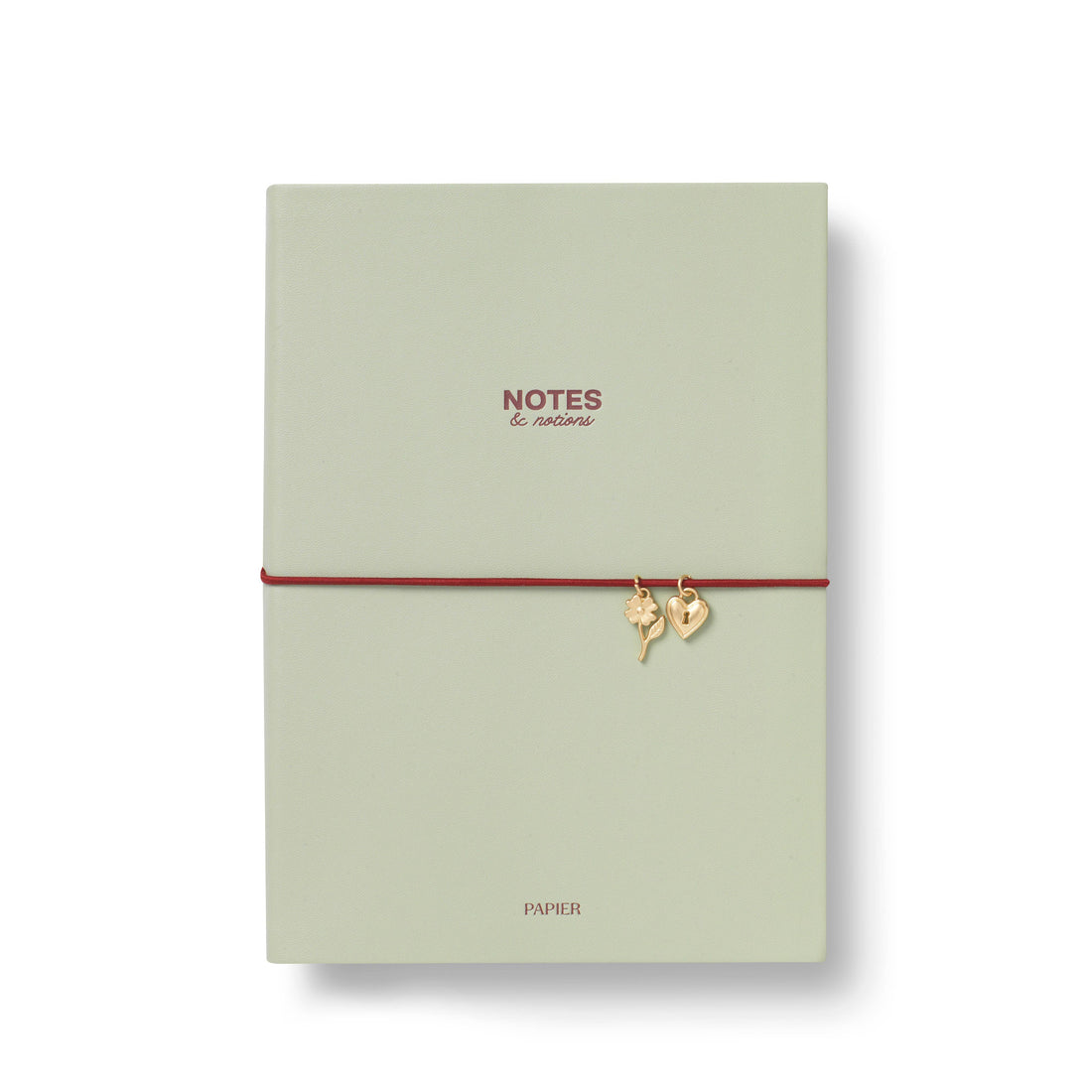 A sage green soft PU cover notebook with a red elastic band closure adorned with two small gold charms A5
