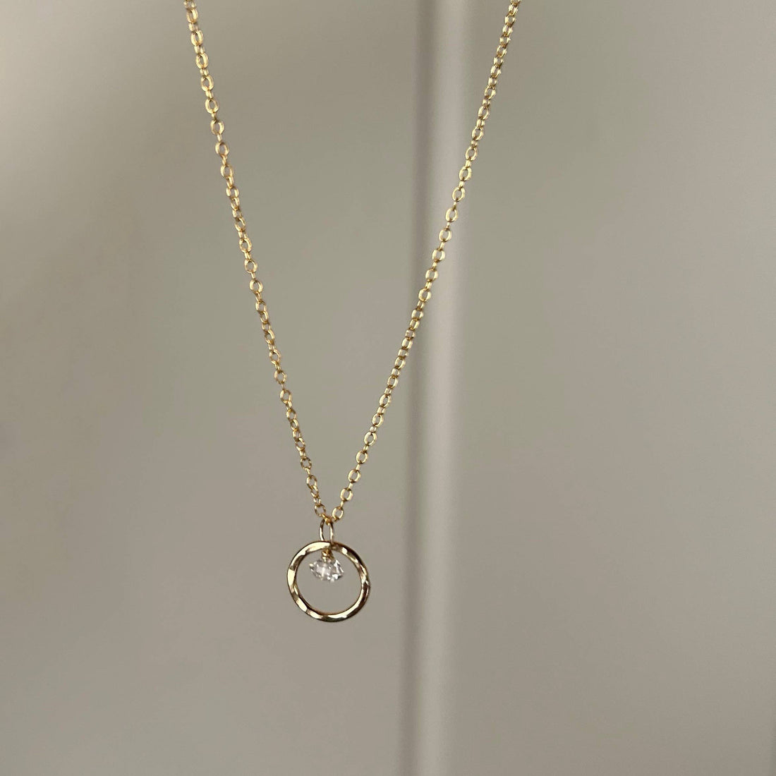 Gold necklace with a circular pendant and a quartz crystal