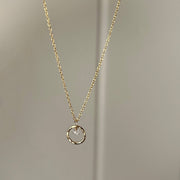 Gold necklace with a circular pendant and a quartz crystal