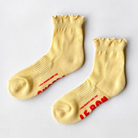 Pair of yellow socks with ruffles and red text 