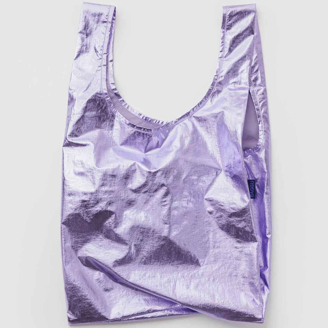 A metallic lavender reusable shopping bag with a wide scoop neckline, laid flat against a light gray background.