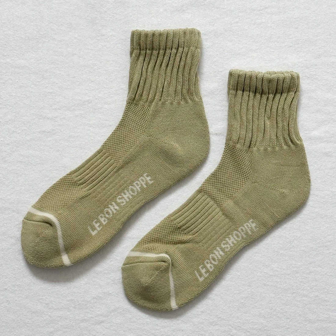 sage colored womens socks with off white  stripe across the toe box