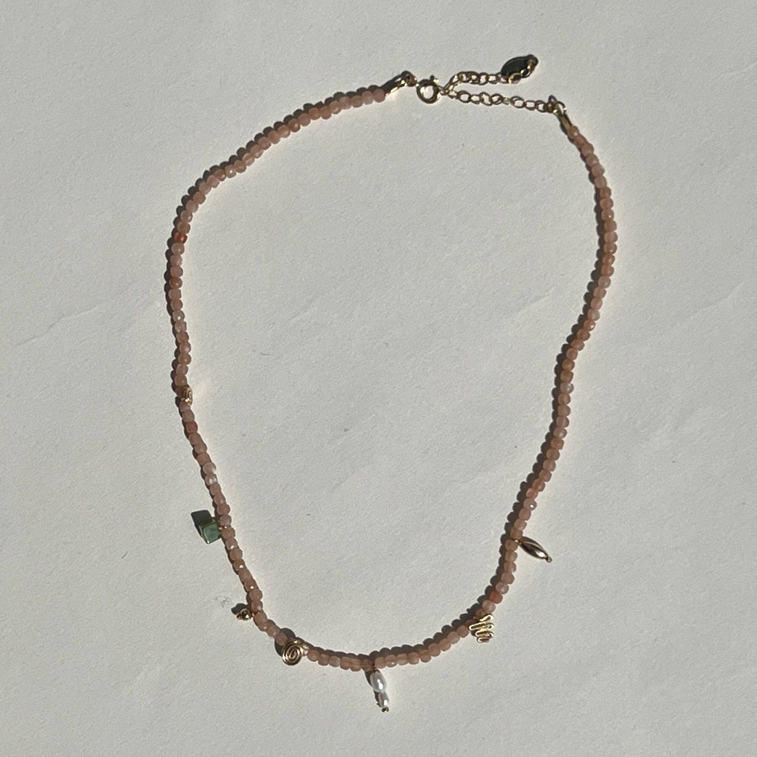 Necklace with small beads and chain on a light gray background