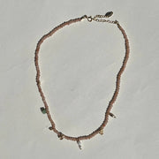 Necklace with small beads and chain on a light gray background