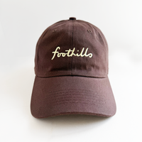 a brown baseball hat with foothills lettering in butter yellow embroidery 