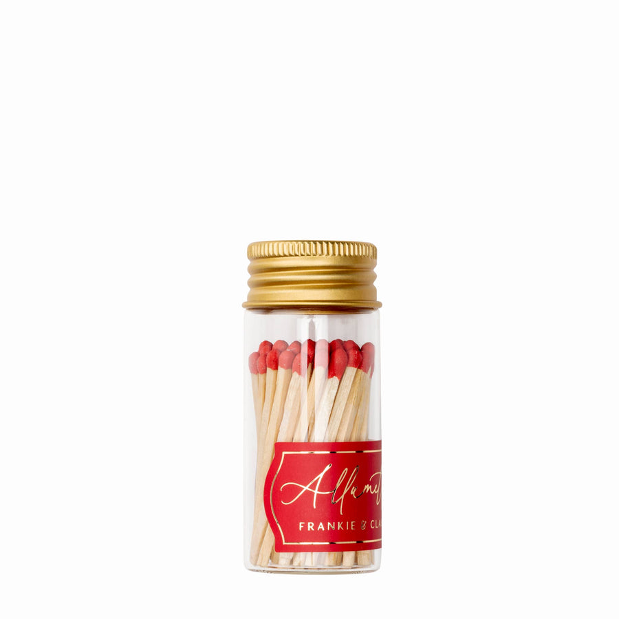 Mini glass match jar with red matches and a gold lid