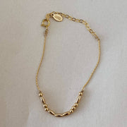 Gold bracelet with beaded design on a light gray background