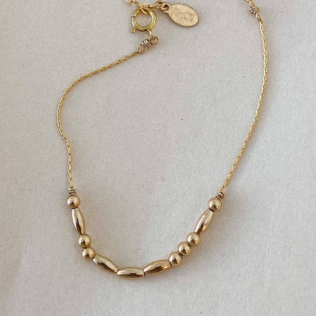 Gold bracelet with beads on a light gray background