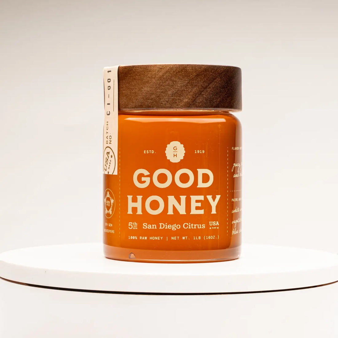 Jar of citrus honey by Good Honey with a wooden lid 