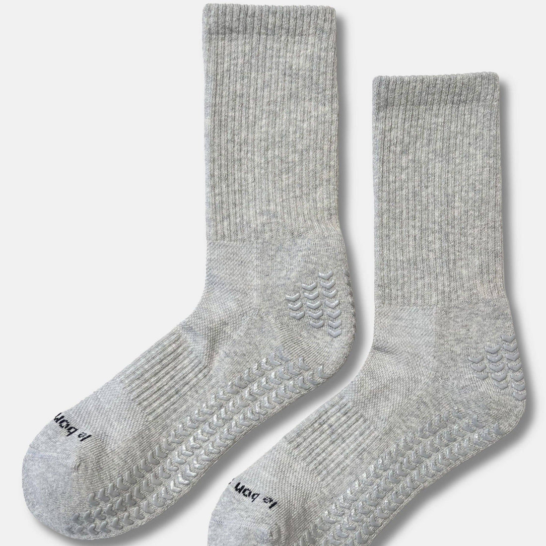 A pair of light gray ribbed knit socks with textured grip patterns on the soles, displayed against a clean off-white background.