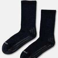 A pair of black grip socks with textured non-slip patterns on the sole and toe, displayed against a light gray background.