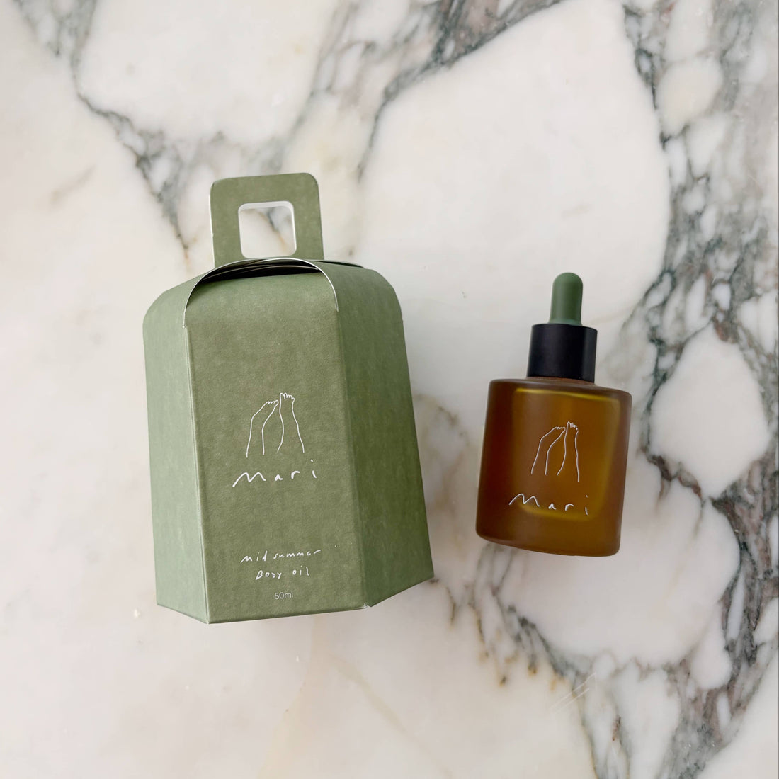 Brown bottle with dropper and green box on a marble surface