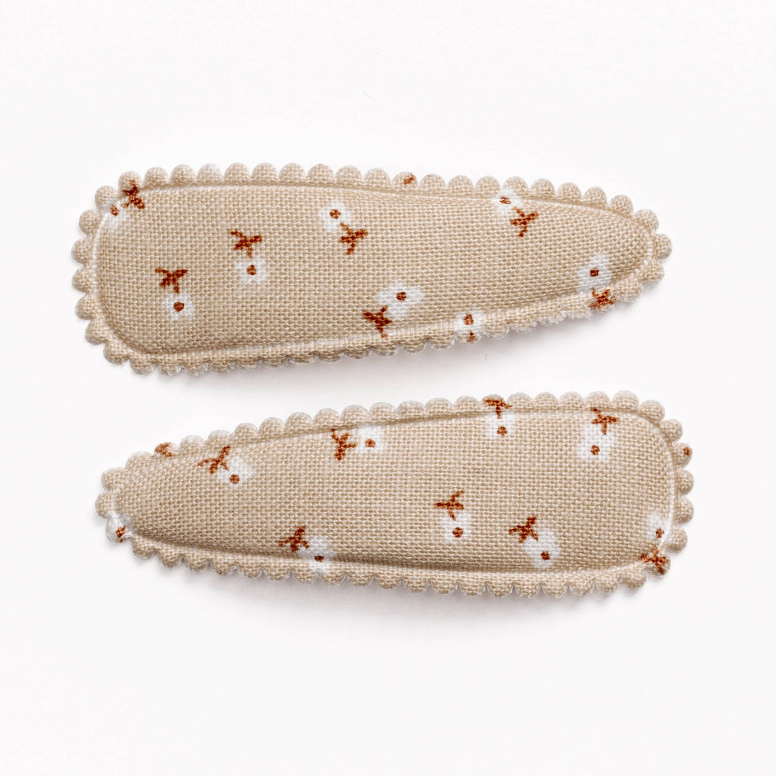 Two beige fabric hair clips with floral pattern