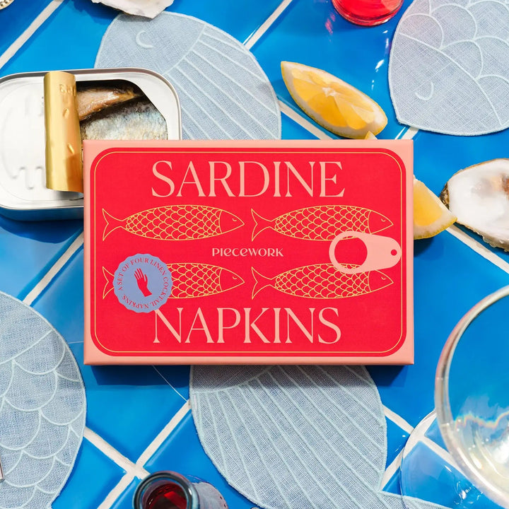 Sardine cocktail napkins on a table with oysters and lemon slices.