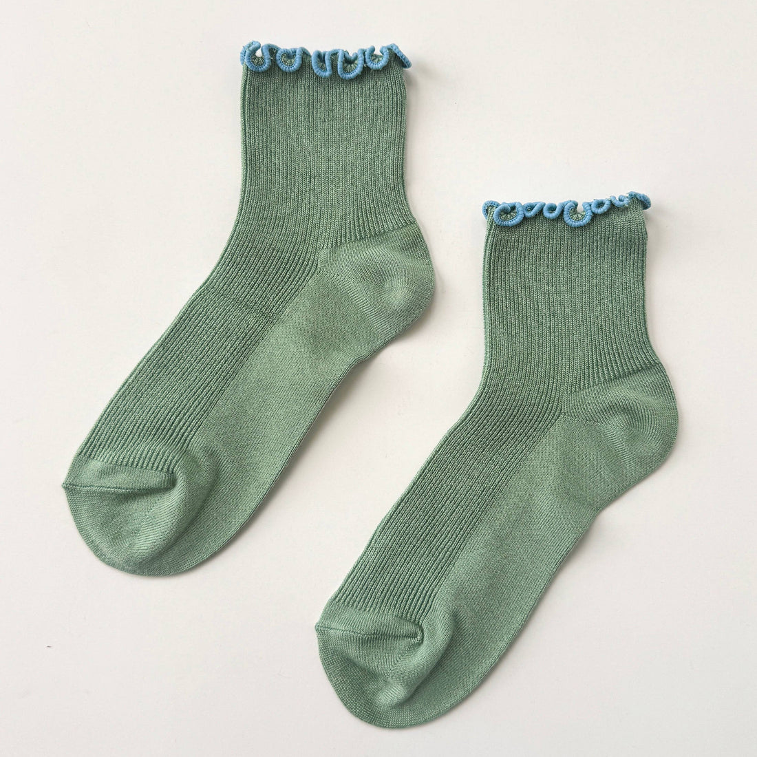 Pair of green socks with blue lace trim on a light gray background