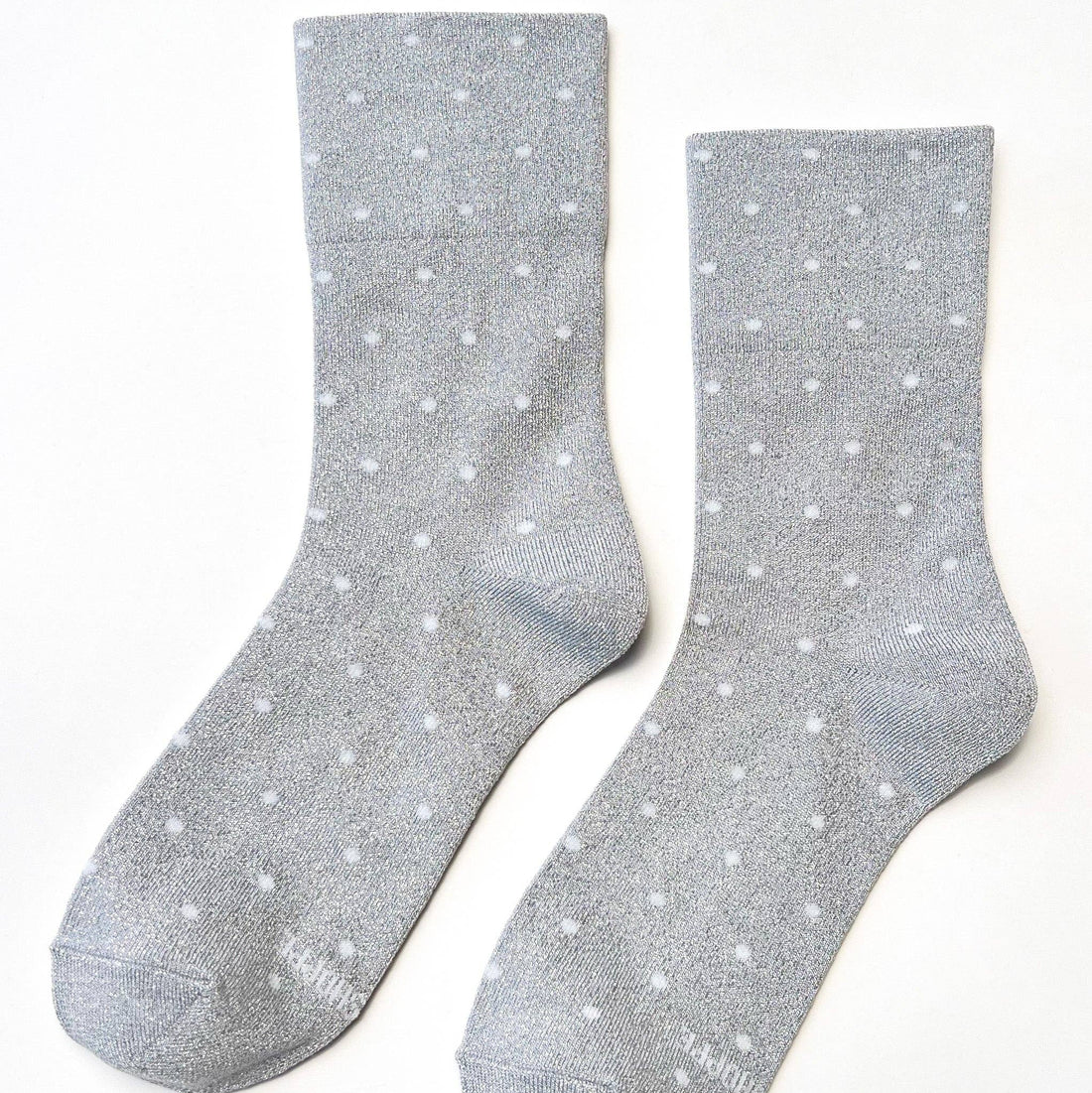 A pair of light gray crew socks with a white polka dot pattern, displayed flat against a clean white background.