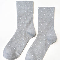 A pair of light gray crew socks with a white polka dot pattern, displayed flat against a clean white background.