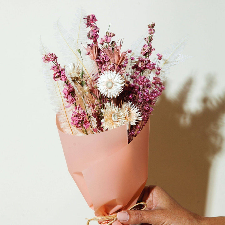 A petite dried bouquet of flowers with colors of bright pink, muted pink, and beige 